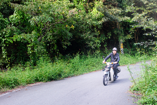 Chef Kawase riding the Super Cub on a mountain road