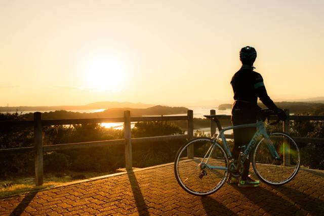 在英虞灣眺望夕陽的單車運動者