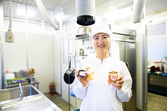 Ms. Sugioka holding some of her products and smiling