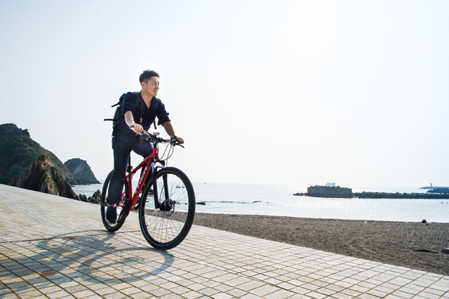 海沿いを自転車で走る今村シェフ